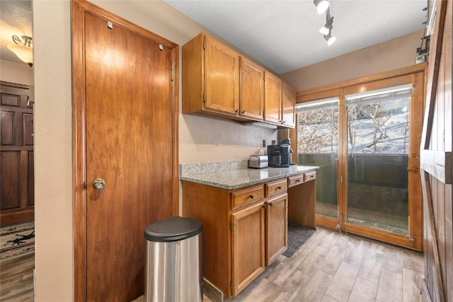 kitchen featuring light stone counters, light hardwood / wood-style flooring, and rail lighting