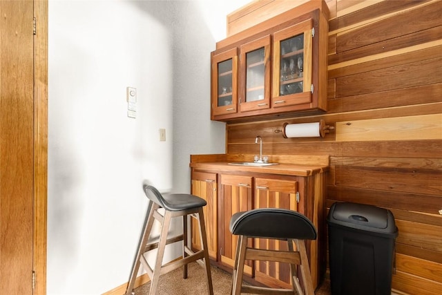 bar featuring butcher block counters, wooden walls, sink, and carpet