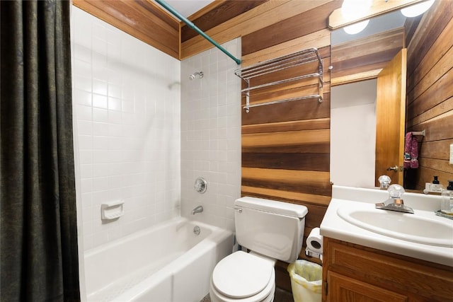 full bathroom featuring vanity, toilet, wooden walls, and tiled shower / bath combo