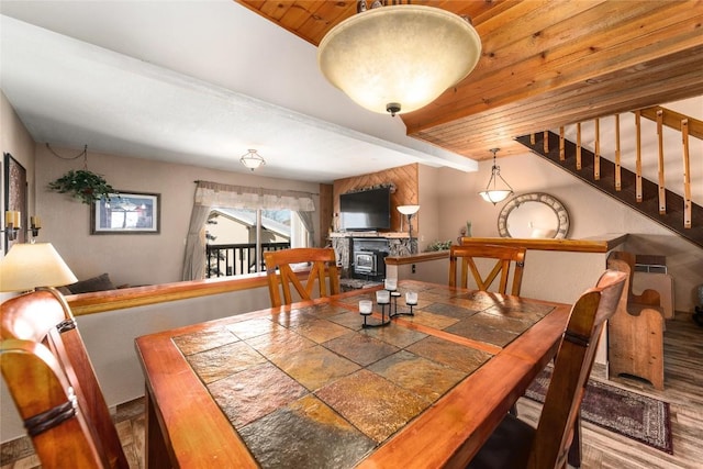 dining room with beam ceiling, a fireplace, wood ceiling, and wood-type flooring