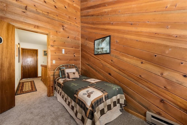 bedroom featuring light carpet, wooden walls, and a baseboard heating unit