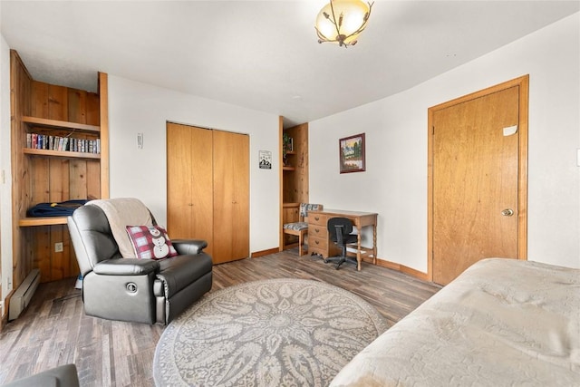 sitting room with built in features, dark wood-type flooring, and a baseboard heating unit