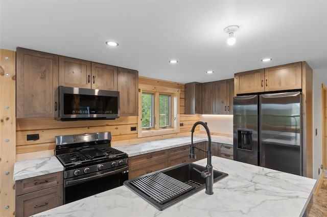 kitchen with light stone countertops, sink, and appliances with stainless steel finishes