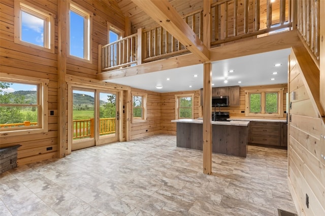 kitchen featuring a kitchen bar, wood walls, a kitchen island, and a high ceiling