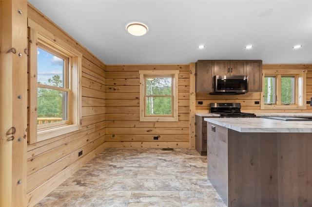 kitchen featuring stainless steel appliances, a healthy amount of sunlight, and wood walls