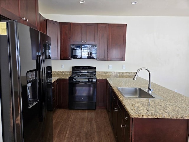 kitchen with light stone counters, dark wood-type flooring, a peninsula, black appliances, and a sink