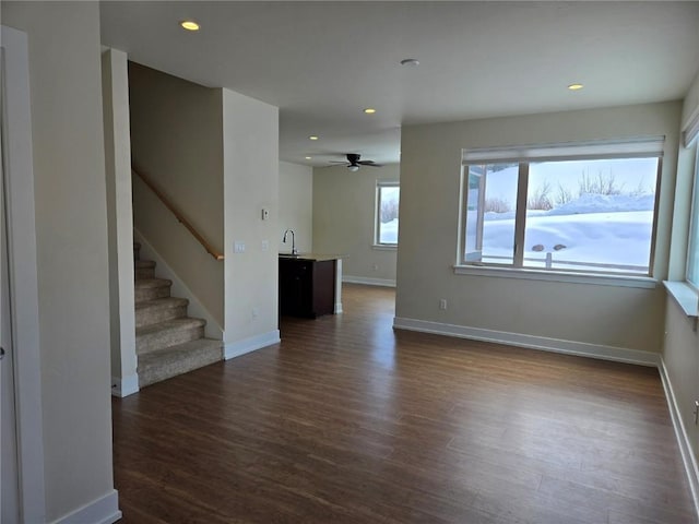 spare room with recessed lighting, dark wood-style flooring, a sink, baseboards, and stairs