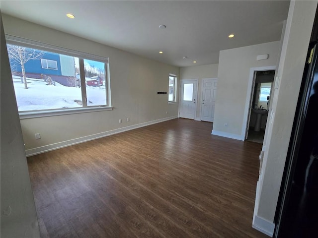 unfurnished living room featuring dark wood-type flooring, recessed lighting, and baseboards