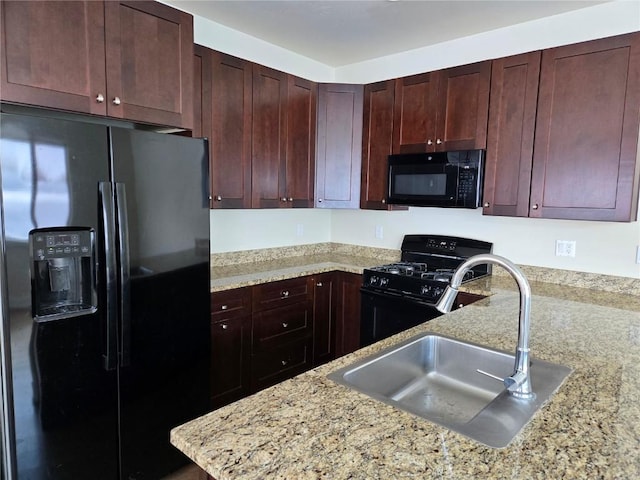 kitchen with black appliances, light stone counters, a peninsula, and a sink