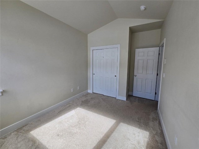 unfurnished bedroom with lofted ceiling, carpet, baseboards, and a closet