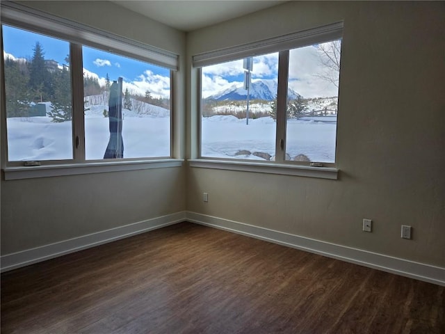 empty room with baseboards, a mountain view, and dark wood-style flooring