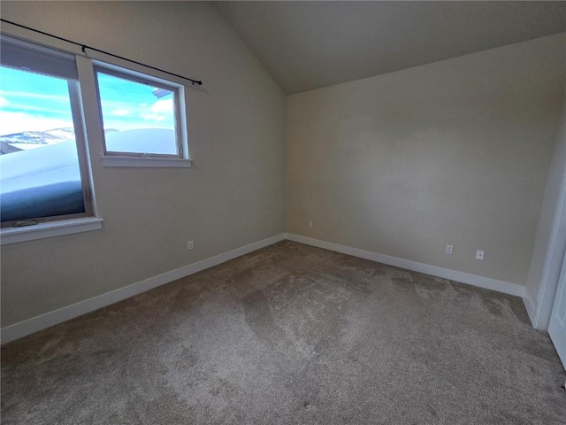 carpeted spare room featuring lofted ceiling and baseboards