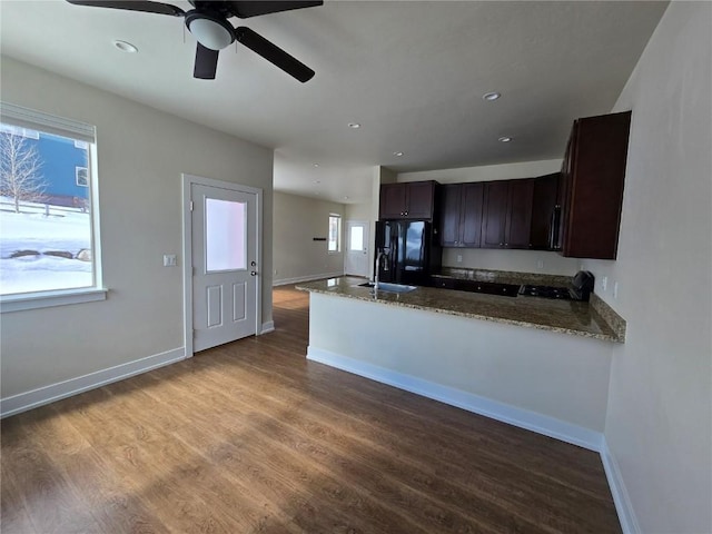 kitchen featuring wood finished floors, dark stone counters, a sink, and black fridge with ice dispenser