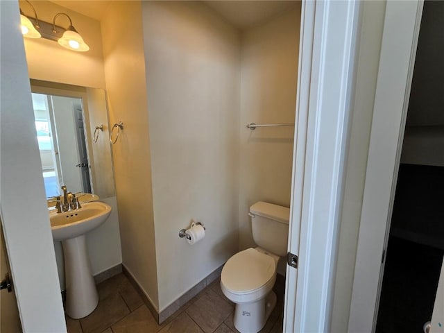 bathroom with a sink, tile patterned flooring, toilet, and baseboards