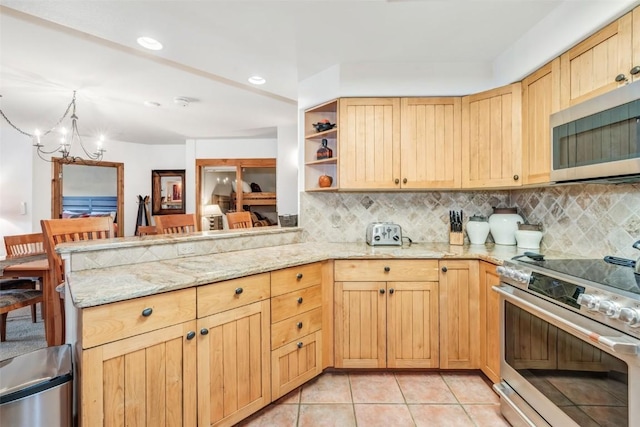 kitchen featuring kitchen peninsula, appliances with stainless steel finishes, light tile patterned floors, and a notable chandelier