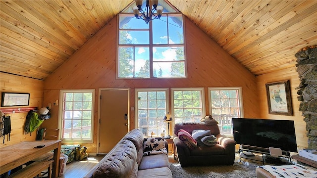 living room featuring a wealth of natural light, high vaulted ceiling, wooden ceiling, a chandelier, and wood walls