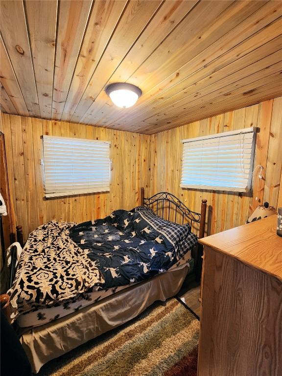 bedroom featuring carpet flooring, wooden walls, and wooden ceiling