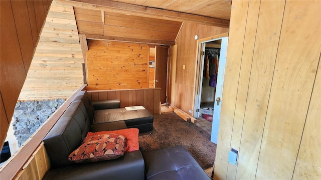 interior space featuring beamed ceiling, wood walls, wood ceiling, and carpet floors