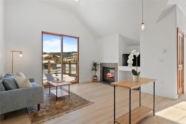 living room featuring light hardwood / wood-style floors, lofted ceiling, and a tile fireplace