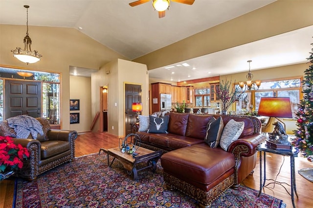 living room with ceiling fan with notable chandelier, light hardwood / wood-style flooring, and lofted ceiling