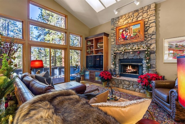 living room featuring a fireplace, high vaulted ceiling, and a skylight