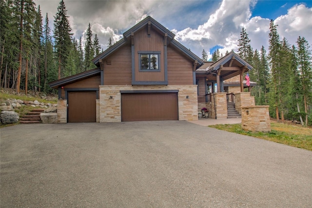 view of front of house with aphalt driveway, a garage, and stone siding