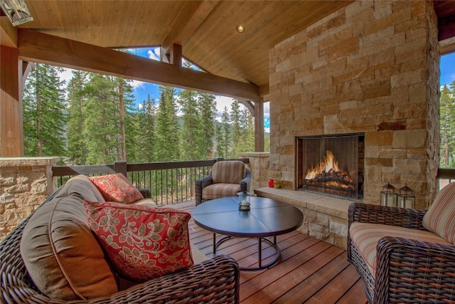 sunroom / solarium with vaulted ceiling with beams, wood ceiling, and an outdoor stone fireplace