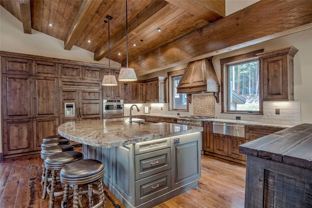 kitchen with a sink, decorative backsplash, custom range hood, wood ceiling, and a warming drawer