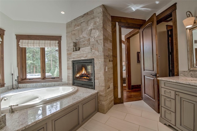 bathroom with vanity, a garden tub, a fireplace, and tile patterned flooring