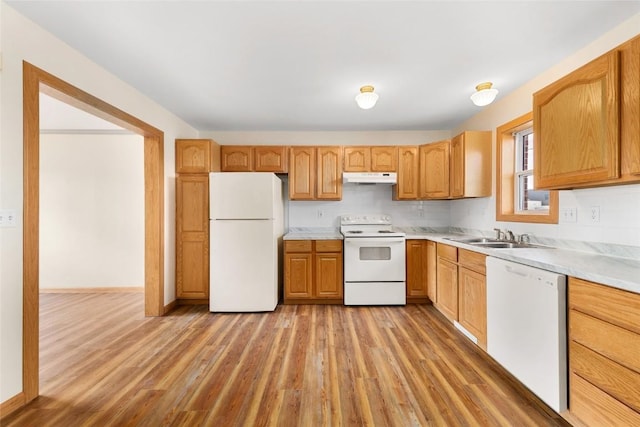 kitchen featuring light wood-type flooring, decorative backsplash, white appliances, and sink