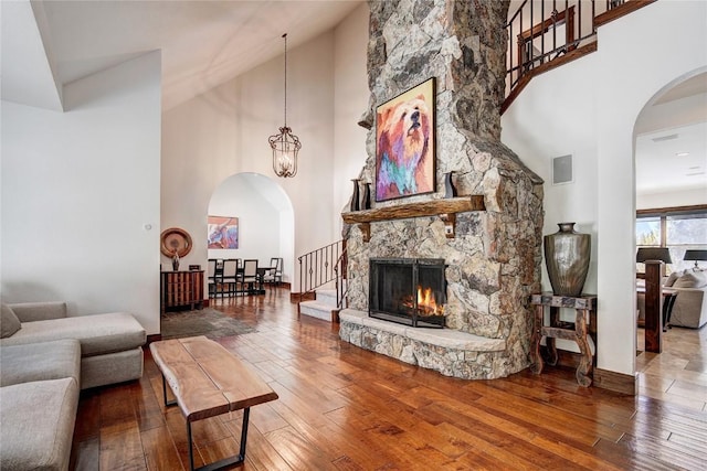 living room featuring a fireplace, high vaulted ceiling, an inviting chandelier, and hardwood / wood-style flooring