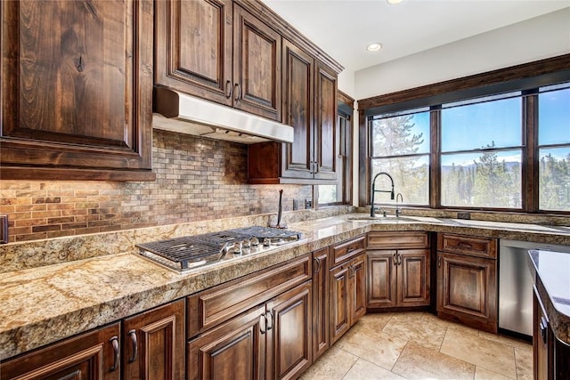 kitchen with appliances with stainless steel finishes, tasteful backsplash, dark brown cabinets, and sink