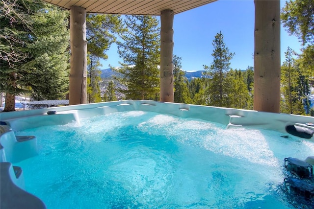 view of swimming pool with a mountain view and a hot tub