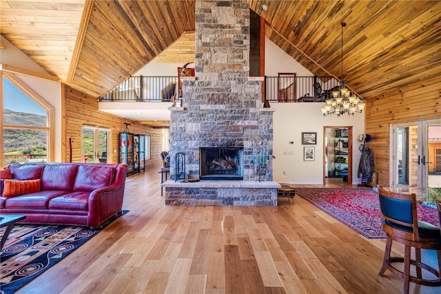 living room featuring a stone fireplace, high vaulted ceiling, wooden walls, wood ceiling, and hardwood / wood-style flooring