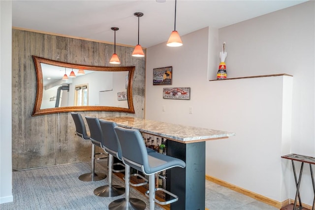 interior space with kitchen peninsula, pendant lighting, a kitchen bar, and wood walls