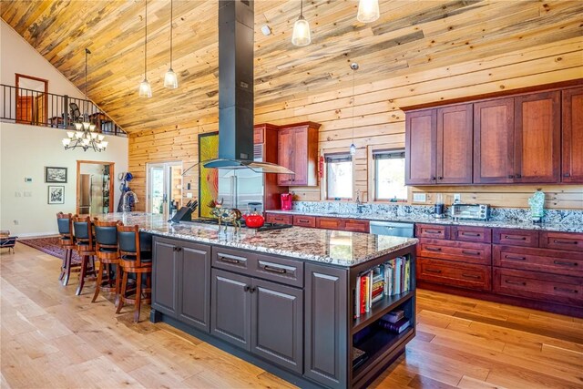 kitchen with light stone counters, high vaulted ceiling, pendant lighting, a kitchen island, and exhaust hood