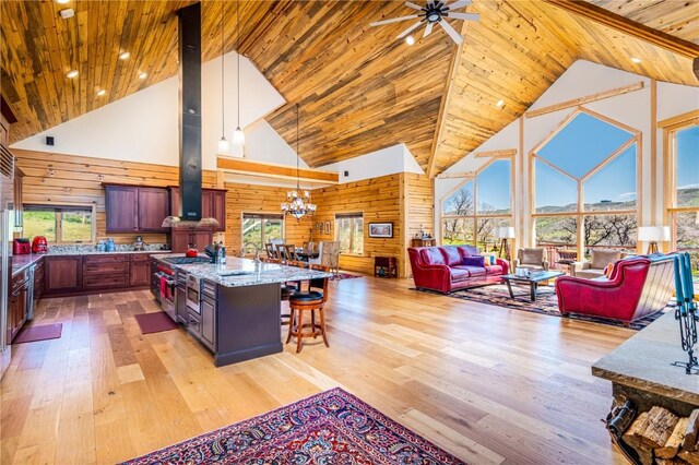 kitchen with a kitchen breakfast bar, light stone counters, high vaulted ceiling, wooden walls, and a kitchen island