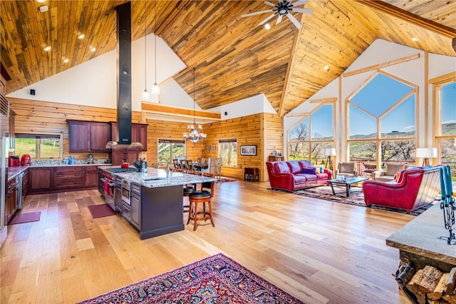 kitchen with a kitchen breakfast bar, light stone counters, high vaulted ceiling, wooden walls, and a kitchen island