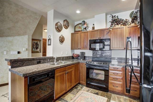 kitchen featuring black appliances, brown cabinetry, a sink, and stone finish floor