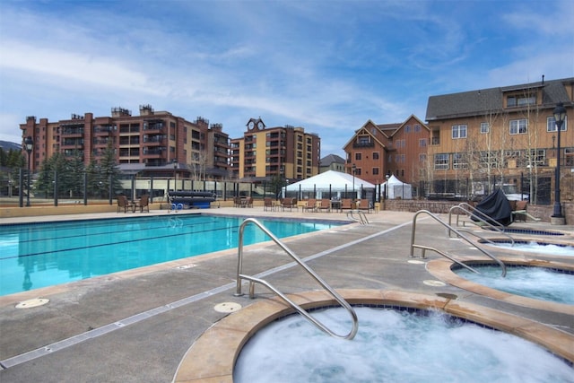 view of swimming pool featuring a patio area, fence, and a hot tub