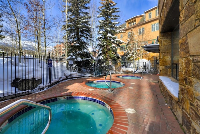 view of swimming pool with a community hot tub and fence