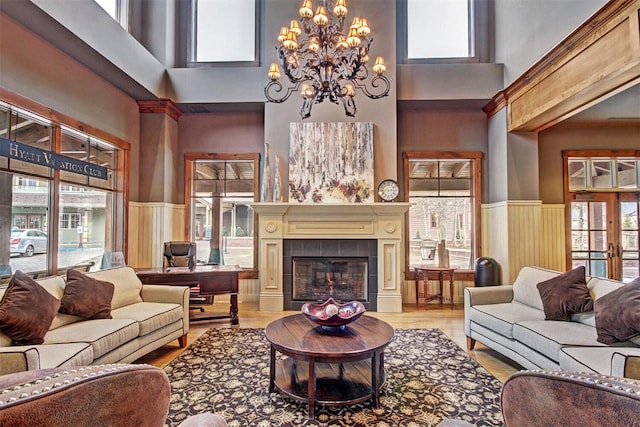 living area with a wainscoted wall, french doors, a tiled fireplace, and wood finished floors