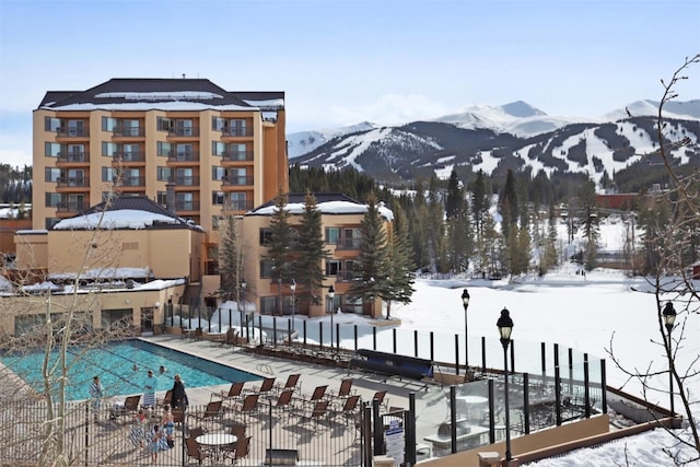 exterior space with a community pool, a mountain view, and fence