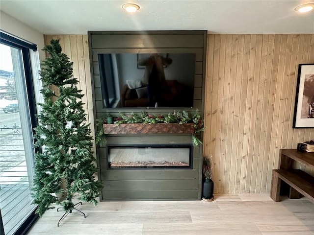 interior space featuring a fireplace, light hardwood / wood-style flooring, and wooden walls