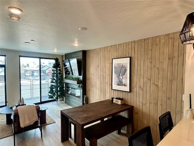 dining space with wooden walls, a fireplace, and light hardwood / wood-style floors