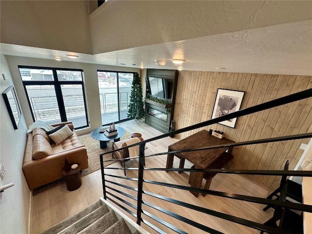 stairs with wood-type flooring, a textured ceiling, a high ceiling, and wood walls