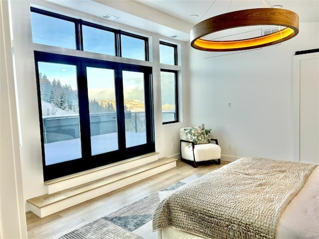 bedroom with wood finished floors, visible vents, and baseboards