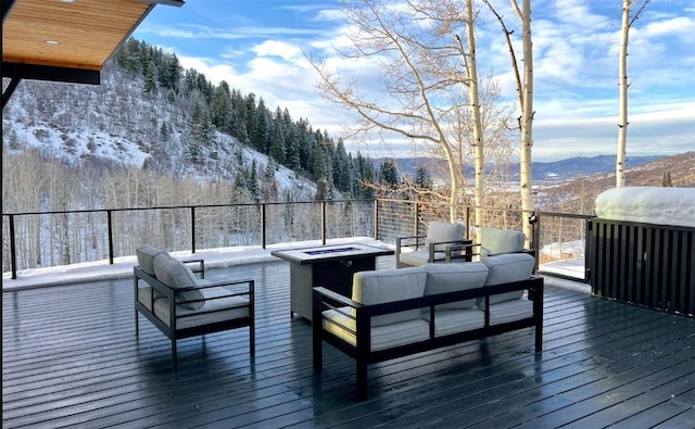 snow covered deck with an outdoor living space with a fire pit and a mountain view