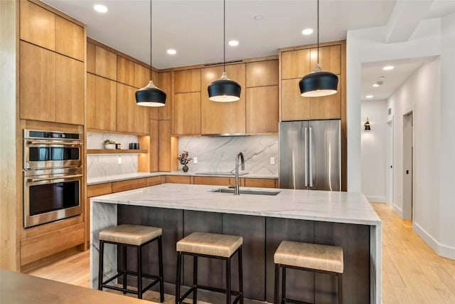 kitchen with stainless steel appliances, a sink, light wood-type flooring, tasteful backsplash, and modern cabinets