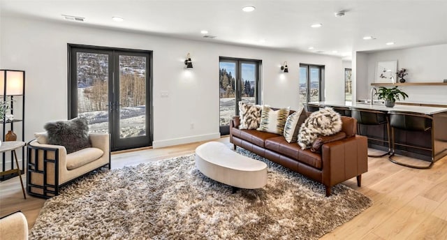 living room with recessed lighting, visible vents, baseboards, light wood-style floors, and french doors